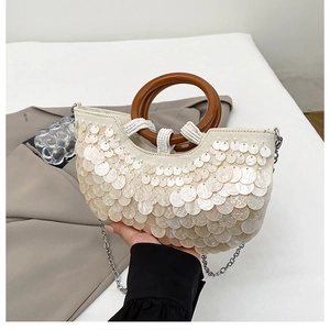 Detail der cremefarbenen Pailletten-Handtasche mit Holzgriff und silberner Kette
