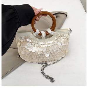 Detail der weißen Muscheltasche mit Pailletten, Holzgriff und silberner Kette