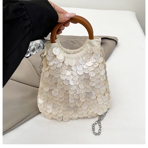 Details einer Muscheltasche mit perlmuttfarbenen Pailletten und runden Holzgriffen