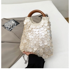 Detail einer Pailletten-Handtasche mit rundem Holzgriff und silberner Kettenriemen