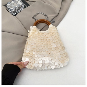 Detail der beigen Muschel-Abendtasche mit rundem Holzgriff und silberner Kette