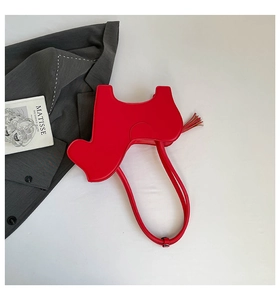 Detail of red cow-shaped leather handbag with tassel charm and matching strap