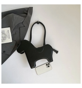 Macro shot of horse-shaped black matte leather bag with fringe tassel and dual handles