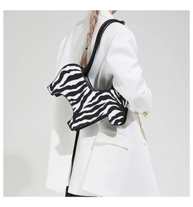 Shoulder shot of zebra print bag with curved profile on a white blazer model