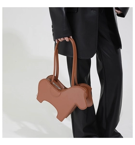 Chic tan leather animal-shaped shoulder bag held by a model in a minimalist studio
