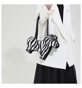 Close-up of zebra pattern handbag with unique animal silhouette on a model in white suit