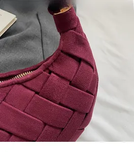 Detail of burgundy woven suede handbag texture with premium gold zipper closure