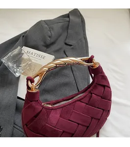 Detail of burgundy woven moon bag featuring a distinctive golden twisted metal handle