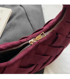 Close-up of woven suede burgundy handbag showing smooth gold-toned metal zipper detail
