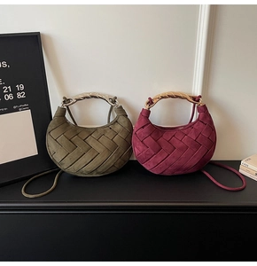 Detail of woven crescent bags in burgundy and dark green with twisted metal handles
