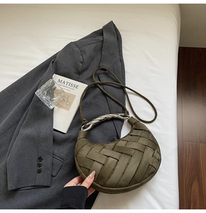 Detail of army green woven crescent bag featuring a twisted silver metal handle accessory
