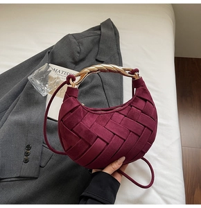 Detail of wine red woven crescent bag with luxury twisted gold metal handle and strap