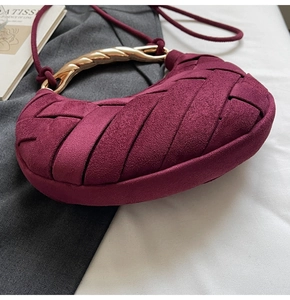 Detail of burgundy suede woven crescent bag with gold twisted metal handle and fine strap