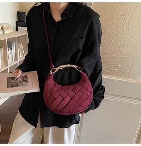 Detail of burgundy woven hobo bag with a distinctive twisted gold metal handle and strap