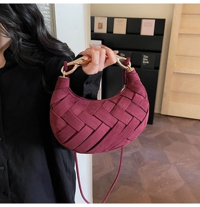 Macro view of burgundy woven texture and sleek gold metal handle on a luxury bag