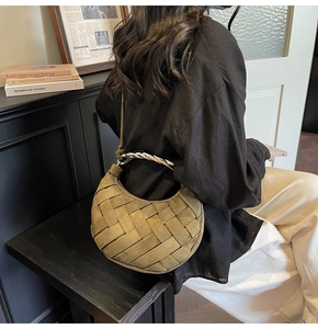 Close-up of olive green suede woven bag with sculptural silver metal handle