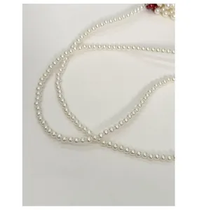 Detail view of round white pearl beaded shoulder strap for mini crossbody earphone bag