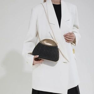 Pochette de soirée tissée noire avec poignées en métal doré et bandoulière sur blazer blanc