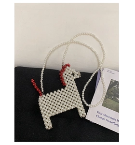Detail of woven pearl crossbody bag in horse shape with red accents and pearl strap