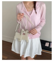 Detail of handmade dog-shaped pearl woven handbags with crossbody straps on a pink bench