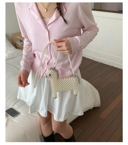 Woven white pearl handbag in a cute horse shape worn by a model in a bedroom setting