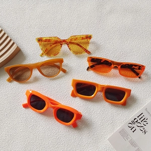 Collezione di occhiali da sole cat-eye arancioni e ambra su sfondo materico minimalista