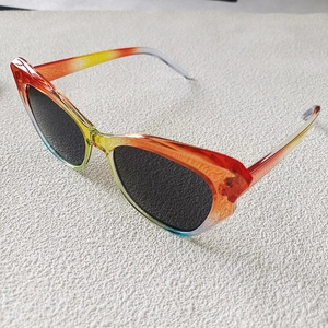 Dettaglio occhiali da sole cat-eye con montura sfumata arcobaleno e lenti scure