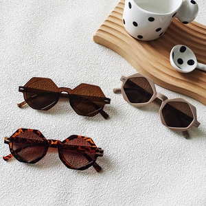 Three pairs of vintage hexagonal sunglasses in tortoiseshell, amber, and matte beige colors