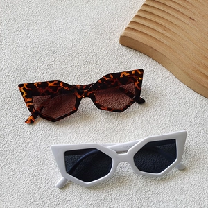 Detail showing geometric cat-eye sunglasses in tortoiseshell and matte white frames