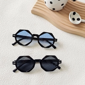 Close-up of hexagonal sunglasses with black frames and gradient blue and grey lenses