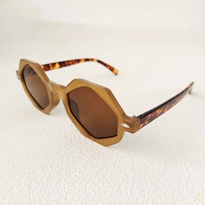 Detailed view of geometric hexagonal sunglasses with amber frames and tortoiseshell temples