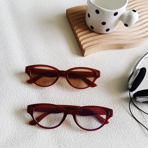 Close-up of retro cat-eye sunglasses with metal rivets on textured white background