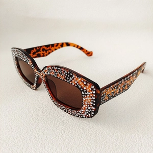 Macro detail of tortoiseshell leopard print sunglasses frame with shimmering crystal rhinestones