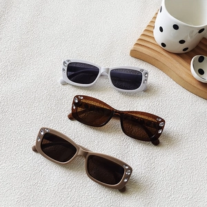 Detailed close-up of three vintage oval sunglasses with rhinestone frames and dark grey lenses