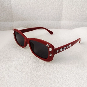 Detail of red rectangle sunglasses frame featuring sparkling rhinestone embellishments