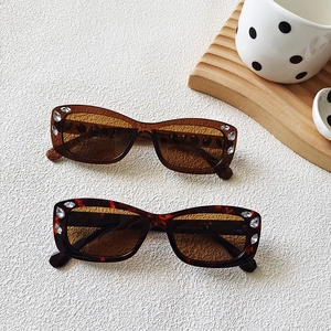 Close-up of small oval sunglasses with rhinestone accents in amber and tortoise finish