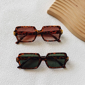 Detail of square tortoiseshell sunglasses with brown and green lenses on wooden decor