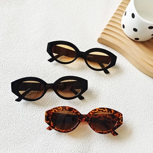 Three pairs of vintage cat-eye sunglasses in tortoise and black frames on a wooden tray
