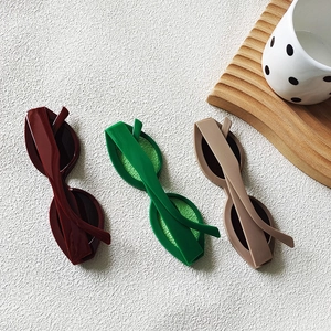 Flat lay of vintage cat-eye sunglasses in burgundy, green and beige on a textured surface