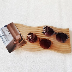 Close-up of stylish oversized sunglasses in amber and transparent grey on wooden stand