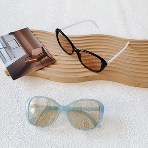 Flat lay of oversized sunglasses in black-white and transparent blue on a textured surface