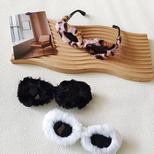 Gafas de sol cat eye de felpa en leopardo, negro y blanco sobre bandeja de madera