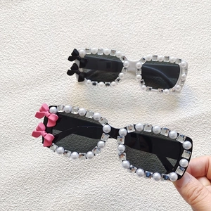 Detail of kids pearl sunglasses with rhinestones and ribbon bows on white frames