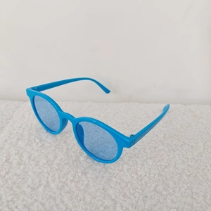 Vue détaillée de lunettes de soleil rondes bleues pour bambins sur un tissu en peluche blanc