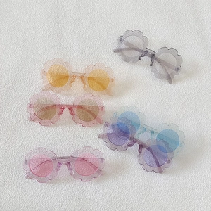 Detailed flat lay of kids' flower-shaped sunglasses in five colorful matte translucent frames
