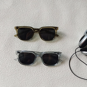 Flat lay detail of minimalist square sunglasses in translucent brown and clear grey frames