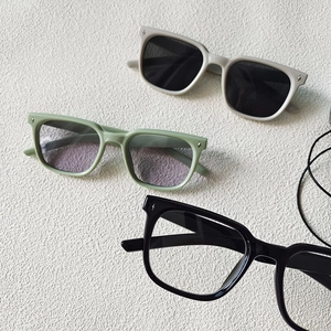 Close-up of square kids' sunglasses with star rivets in white, green, and black