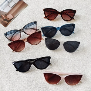 Flat lay of cat-eye sunglasses in seven assorted colors on a textured white background