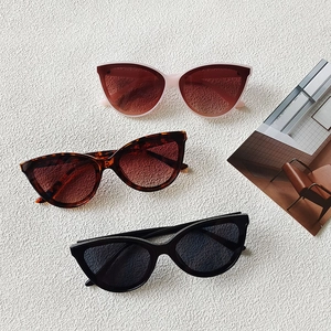 Three retro cat-eye sunglasses in brown gradient and black lenses on a textured background