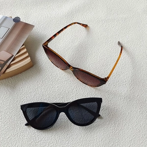 Flat lay of brown tortoise and black oversized sunglasses on a textured white background